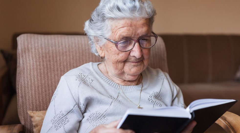 Elderly woman reading a book during respite care